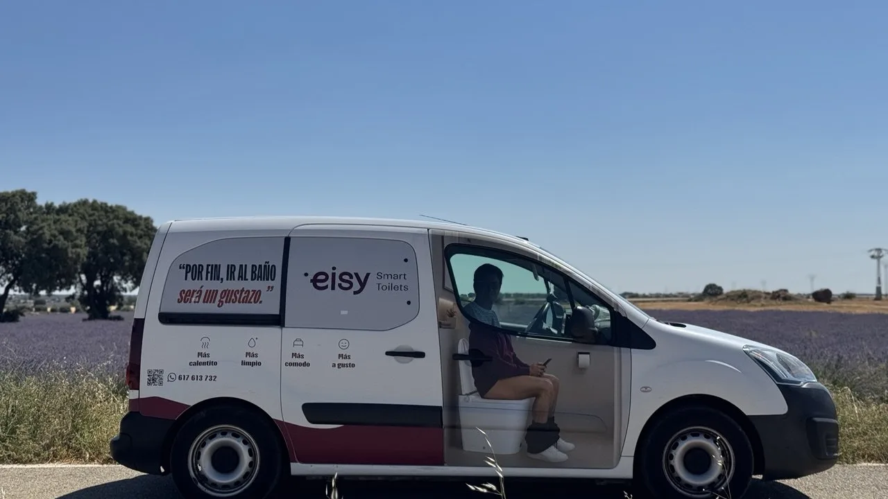 Furgoneta de Eisy rotulada con un inodoro inteligente, aparcada junto a campos de lavanda